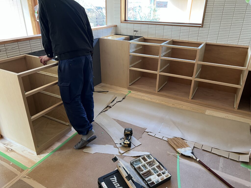 現場で寸法を合わせながら組み立てる木製キッチンのキャビネット